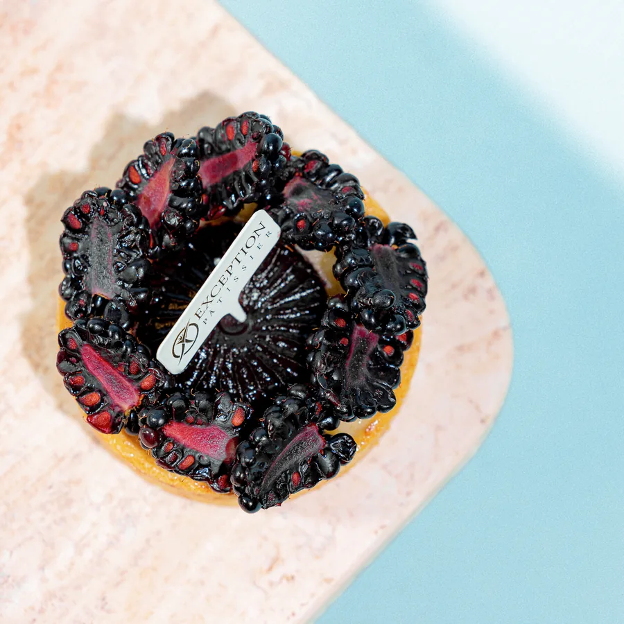 A blackberry tart on pink stone, from Exception Sweets